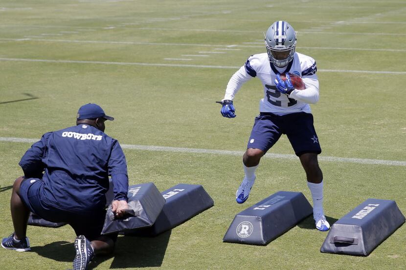 Dallas Cowboys running backs coach Gary Brown, left, instructs Ezekiel Elliott in a running...