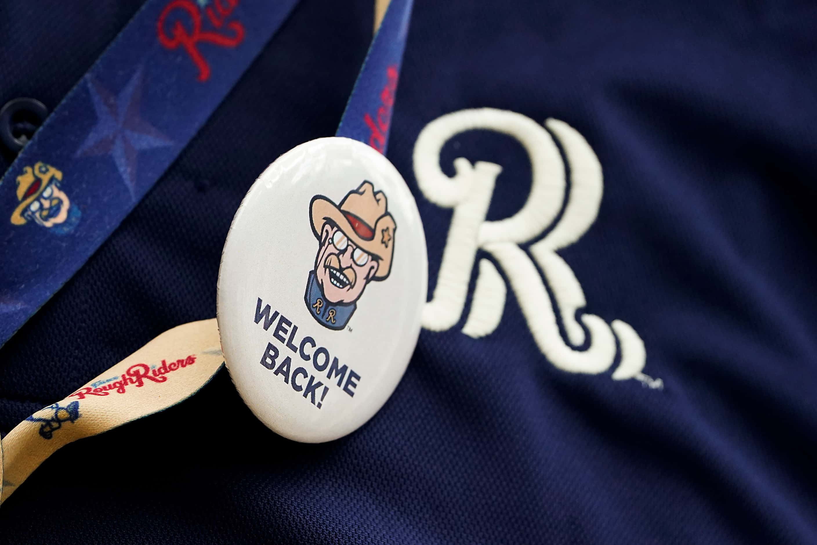A stadium worker wears a “Welcome Back!” button before the Frisco RoughRiders season opener...