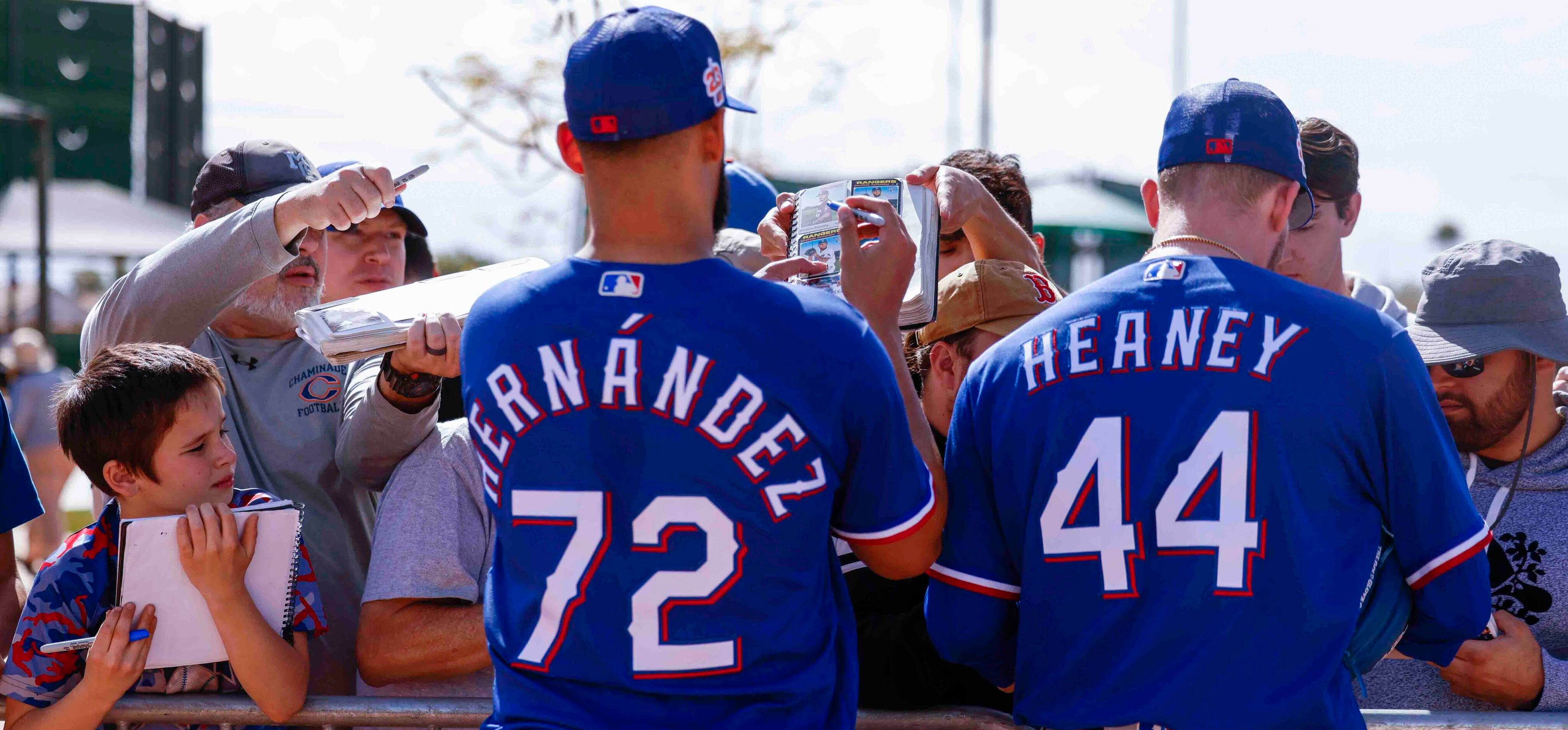 Texas Rangers pitchers Jonathan Hernández, left, and Andrew Heaney sign autographs to the...