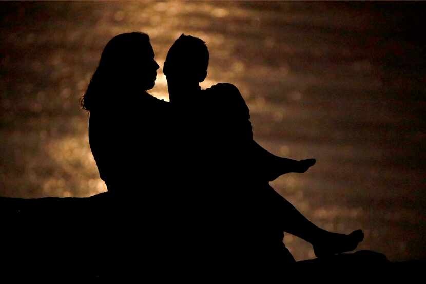 Silueta de una pareja que conversa bajo la luz de la luna en la ribera del río Missouri en...