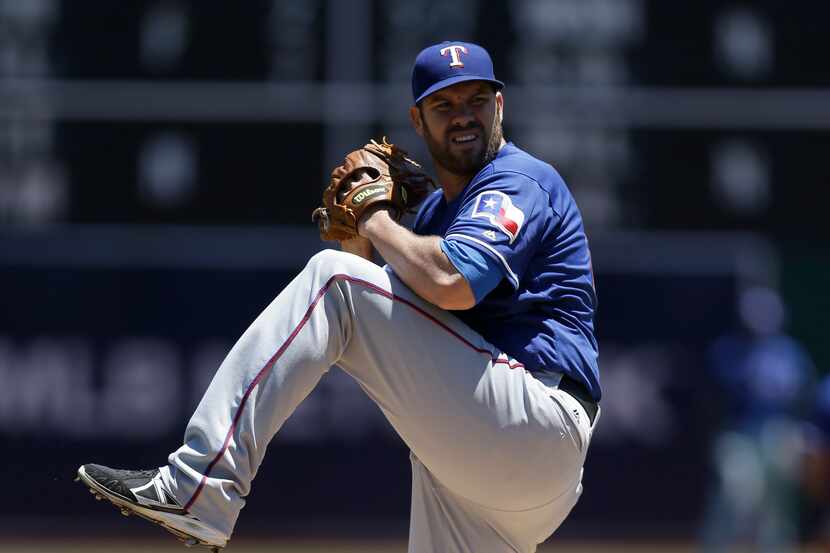 Texas Rangers pitcher Colby Lewis works against the Oakland Athletics in the first inning of...