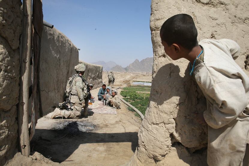 A young boy watches as soldiers from the U.S. Army's 4th squadron 2d Cavalry Regiment pause...