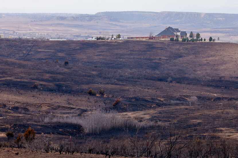 A house untouched by the Smokehouse Creek Fire sits on a hill above charred grasslands,...