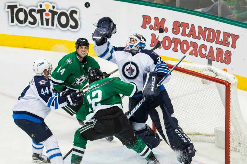 Winnipeg Jets goalie Michael Hutchinson (34) reaches up to catch a puck after a goal attempt...