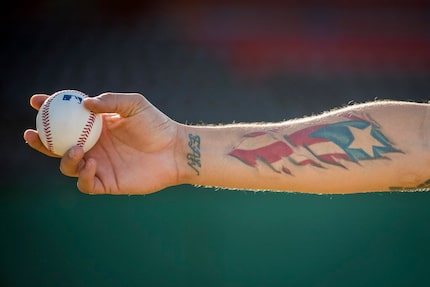 Texas Rangers pitcher Alex Claudio shows off the tattoo of the Puerto Rican flag on his...