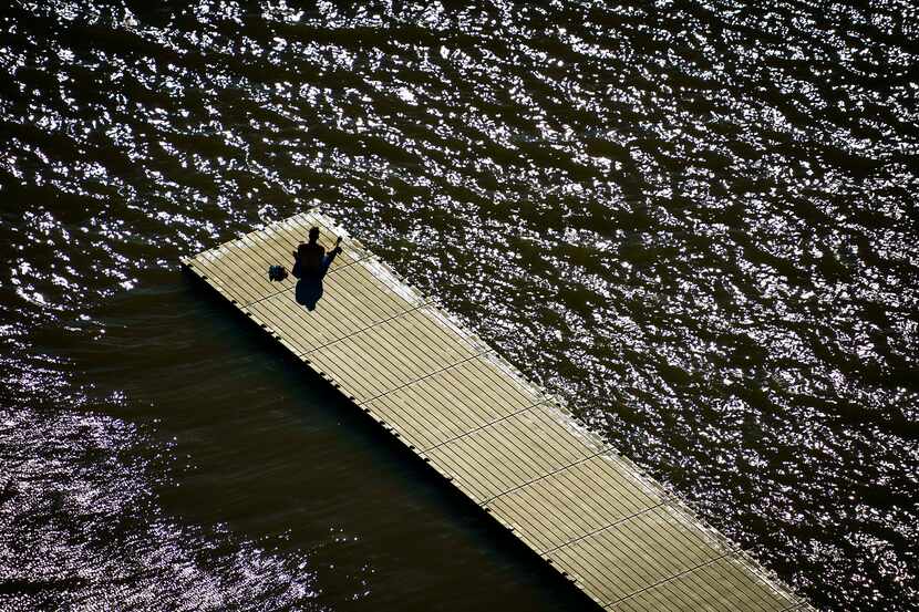 Aerial view of a solitary man sitting on a boat dock at White Rock Lake in Dallas. (Smiley...