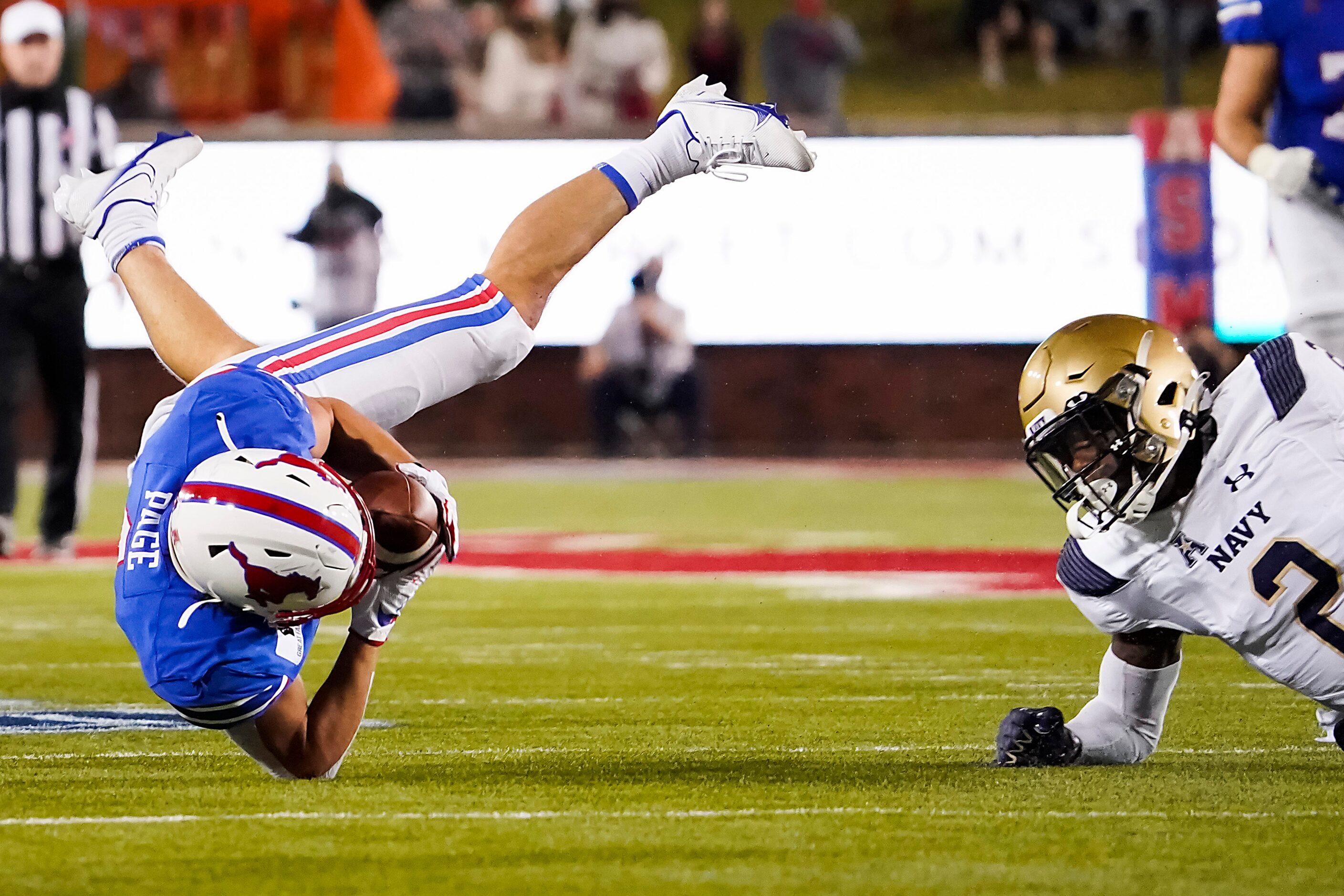 SMU wide receiver Tyler Page (4) is knocked off his feet by Navy cornerback Marcus Wiggins...