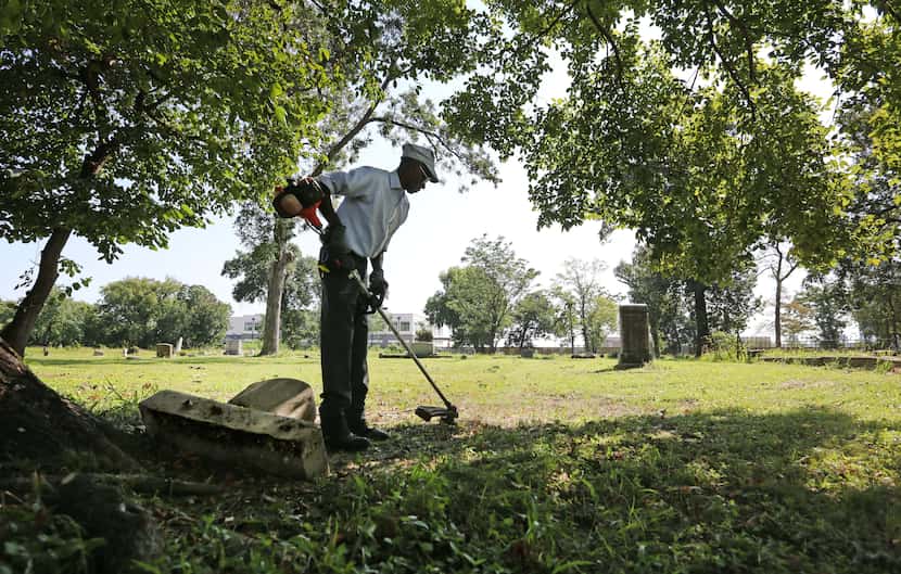 Charles Cook, groundskeeper at Olivewood Cemetery in Houston, works at cutting the grass...