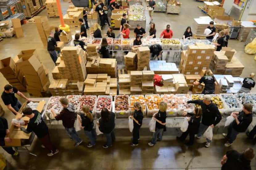 Volunteers from Saville, Dodgen and Co.  pack meals for the Food 4 Kids program, which...