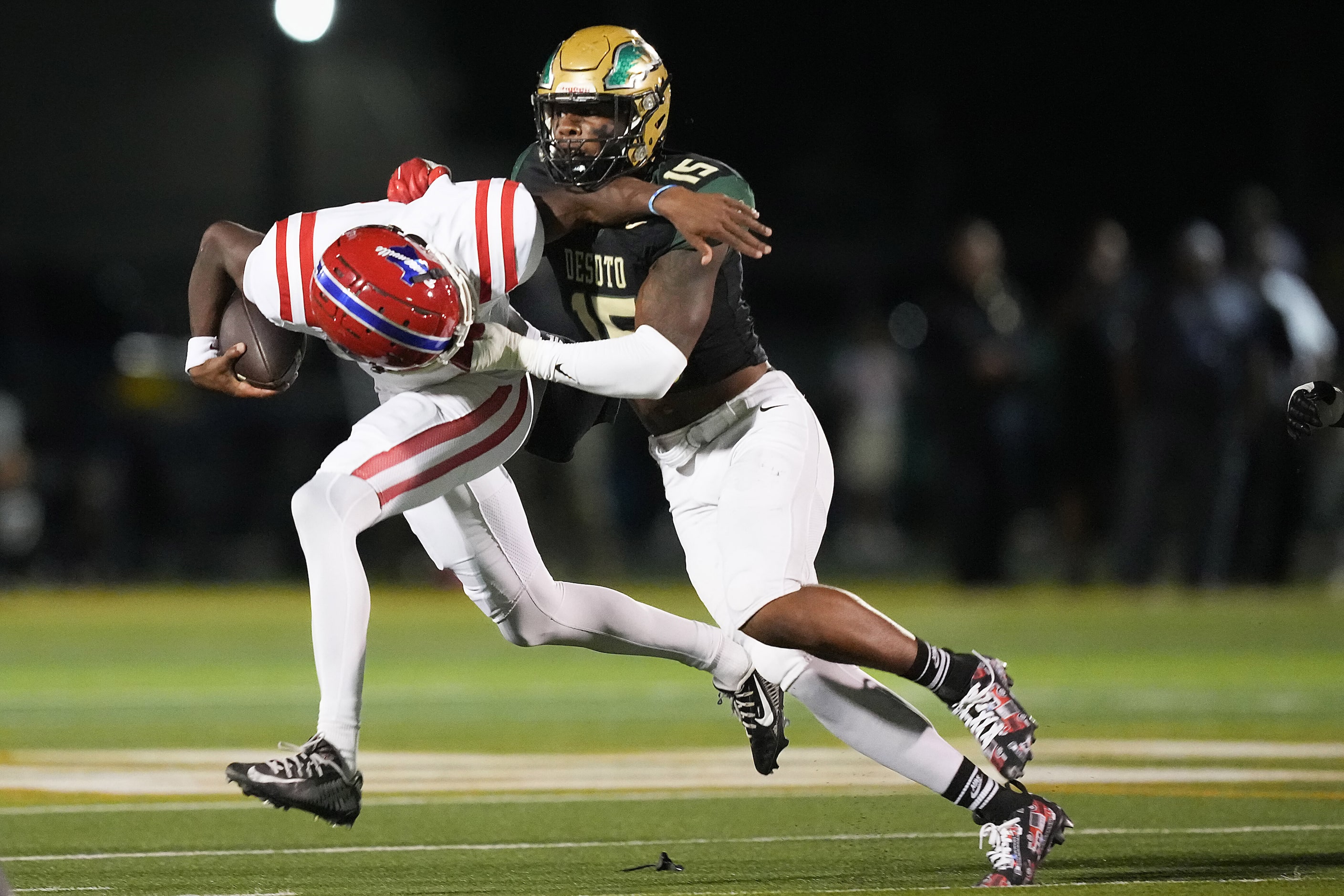 Duncanville quarterback Keelon Russell (12) is brought down by DeSoto defensive lineman...