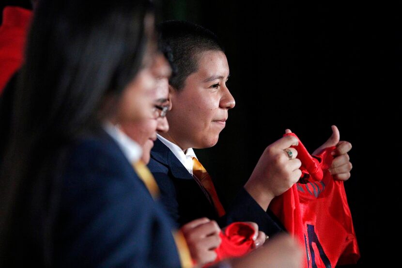 
Ninth-grader Alfonso Avila holds a shirt from his future employer, Dal-Tile, at Friday’s...