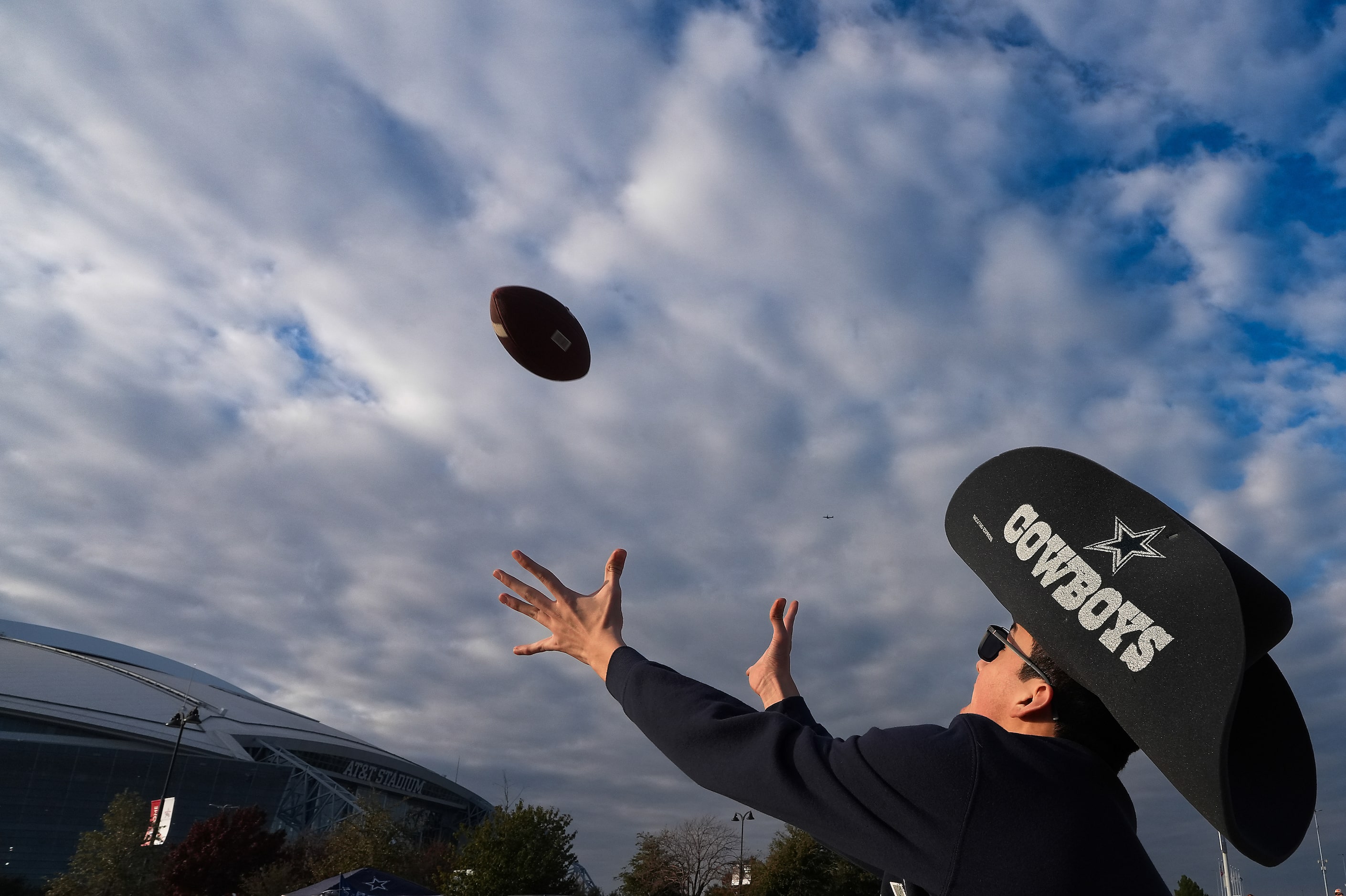 Dallas Cowboys fan Nicolas Reyes reaches for a football while playing catch in the parking...