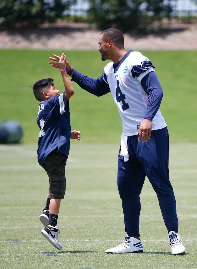 Dak Prescott (4) high fives RayRay Melgarejo, 9, from Make-A-Wish-Foundation during the...