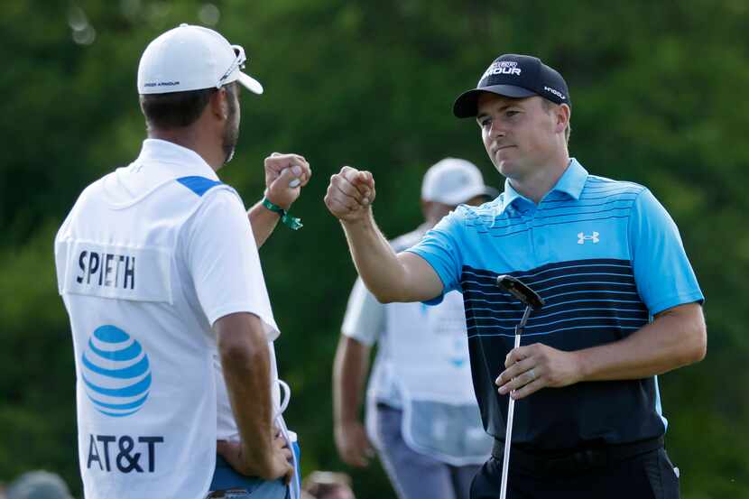 Jordan Spieth and caddie Michael Greller bump fists after Spieth hit an eagle on the 18th...