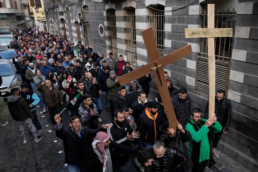 Syrian Christians carry crosses and shout slogans in Damascus, Syria, Tuesday, Dec. 24,...