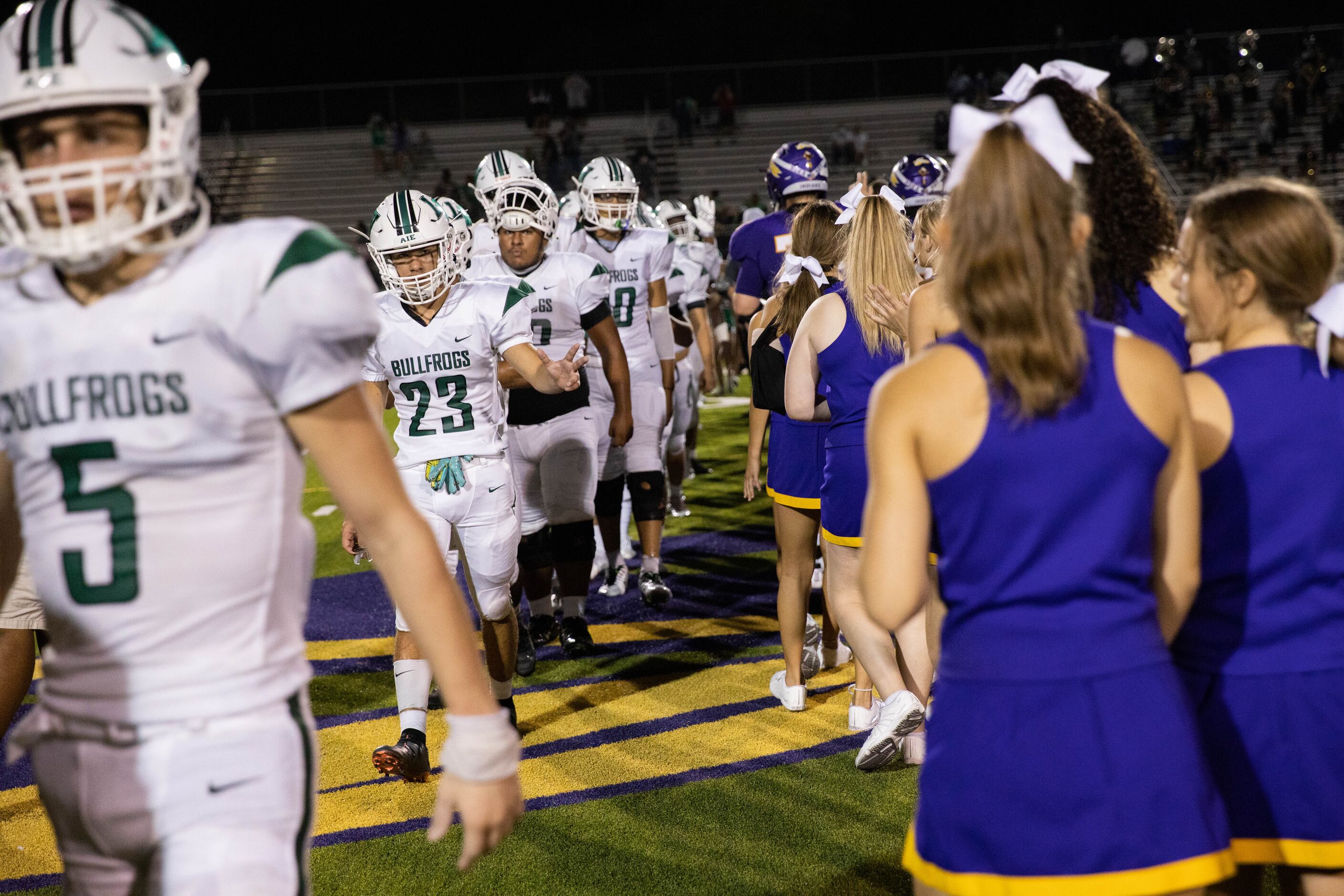 Sanger High School players and cheerleaders (right) walk by Lake Worth High School players...