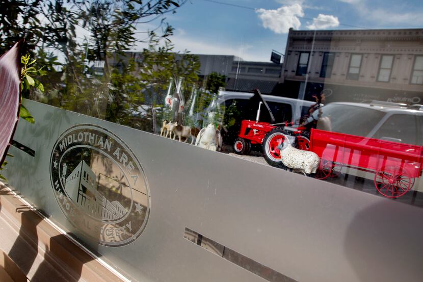 Parts of old downtown Midlothian are reflected in a window display of historical items....