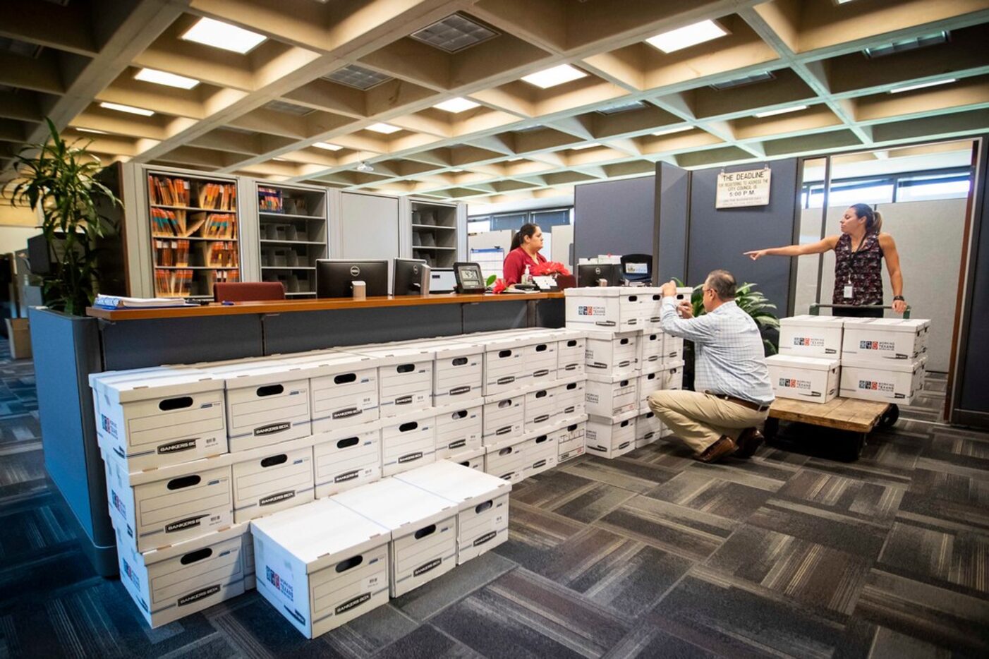 Assistant city secretary Jesus Salazar (center) stacks and counts boxes of petitions after a...