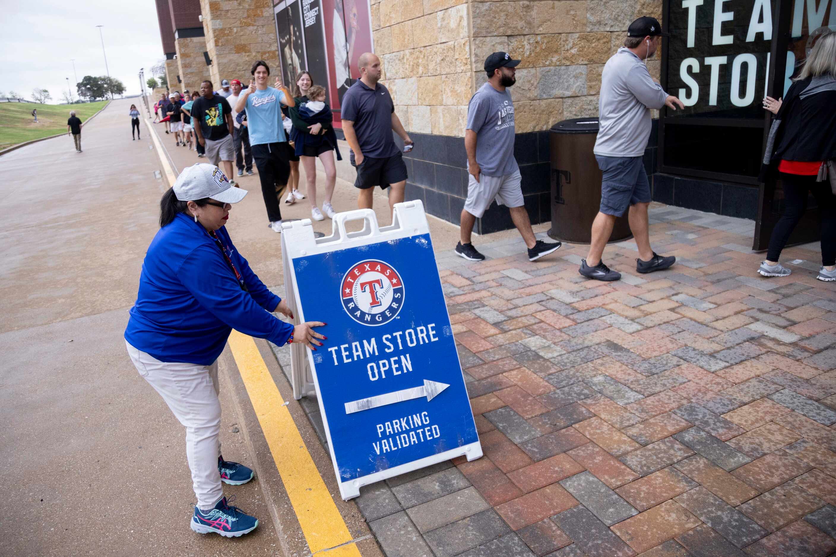 Retail supervisor Carmen Delgado places an open sign as fans enter the Grand Slam Team Store...