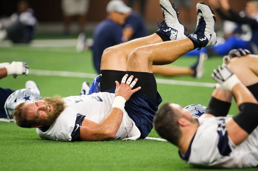 Dallas Cowboys center Travis Frederick (72) laughs while stretching with teammates during a...