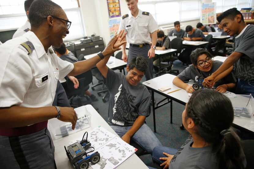 Cadet Lt. James Gray (from left) gives a high five to Steven Godinez, 13, with Katherine...