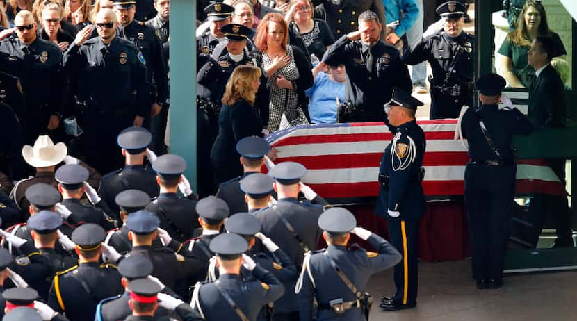 The casket of Little Elm police detective Jerry Walker is rolled from the funeral service to...