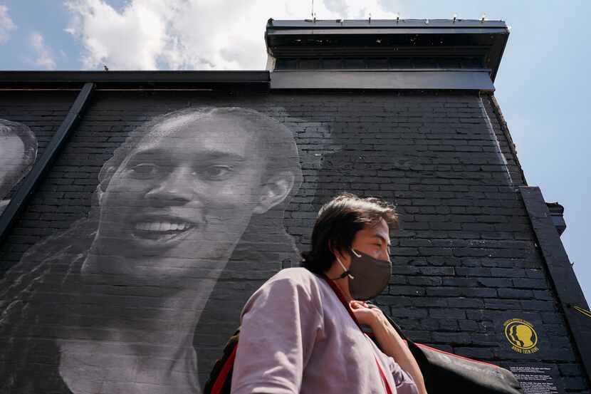A visitor walks down an alley past a mural depicting WNBA star Brittney Griner, top left,...