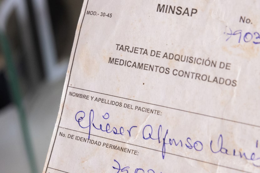 Yennissey Paz, from Santiago de Cuba, holds her husband’s white card with the medical record...