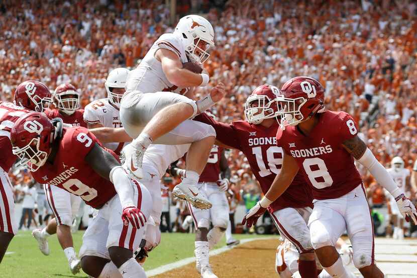 Texas Longhorns quarterback Sam Ehlinger (11) leaps over Oklahoma Sooners linebacker Kenneth...