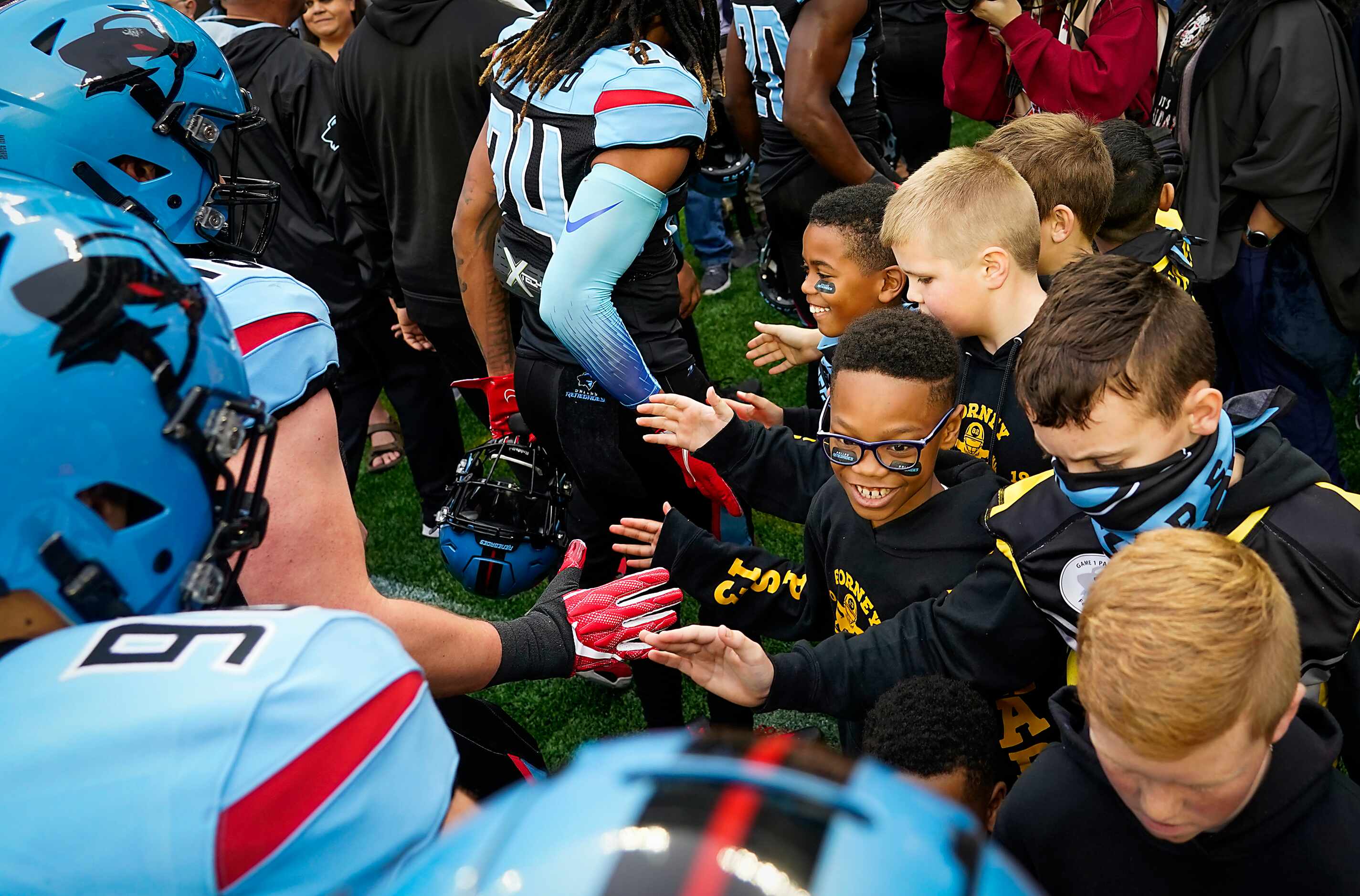 Dallas Renegades players high five members of the Forney Jackrabbits youth football team...