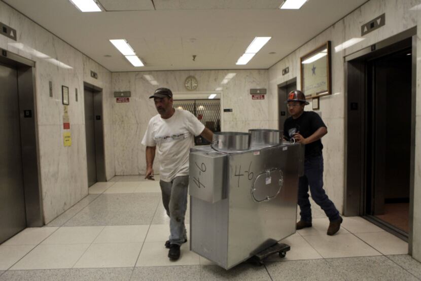 Dennis Jones (left) and Juan Montesinos roll the air distribution boxes hrough the halls....