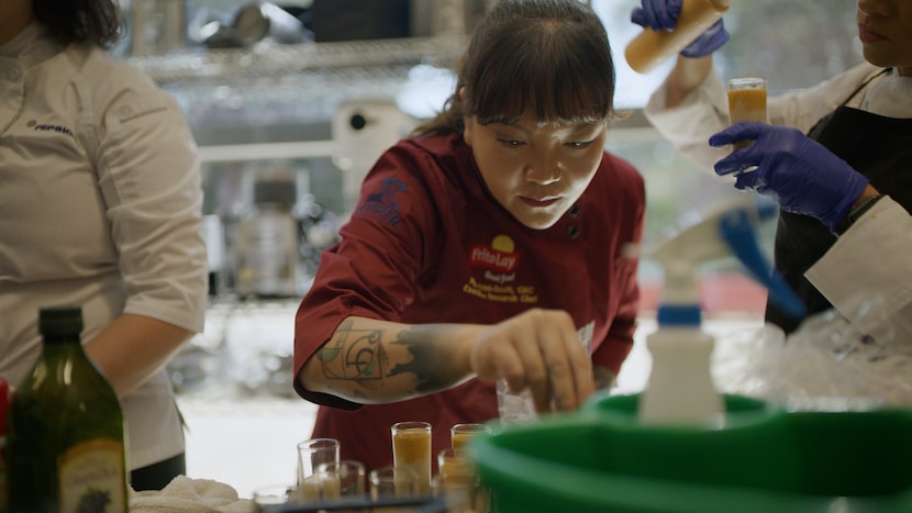 Female chef Ngoc Trinh in a kitchen putting the finishing touch on a meal she just created.