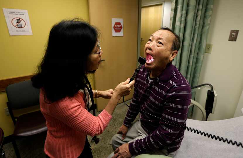 Chan Lai Ly, right, has his mouth examined by Honghue Duong, a physician's assistant, as...