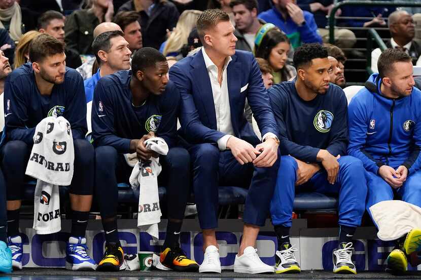Kristaps Porzingis watches from the bench during the first half of an NBA basketball game...