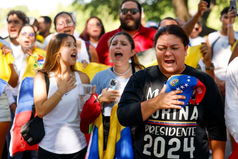 Daniela Borges (right) sings the Venezuelan National Anthem alongside other supporters as...