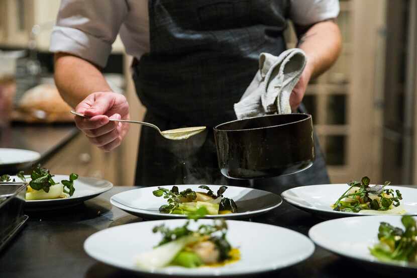 Chef Casey La Rue plates seared scallops with spring onion, fennel and crab reduction as he...