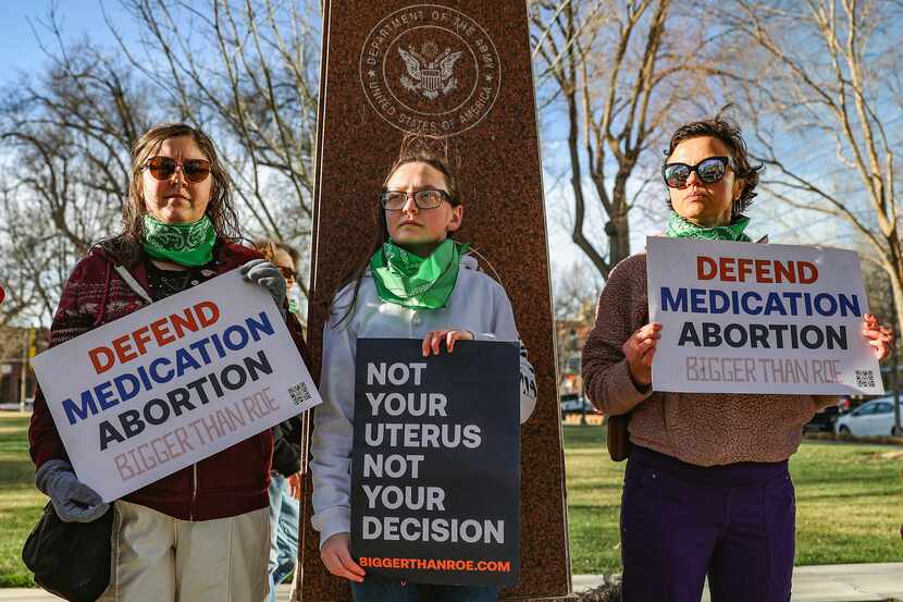 Three members of the Women's March group protest in support of access to abortion medication...