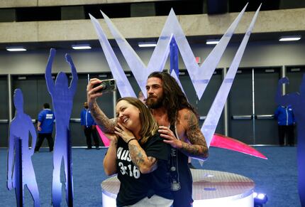 Shane Thomas, back, takes a selfie with Jessica in front of a WWE symbol during an...