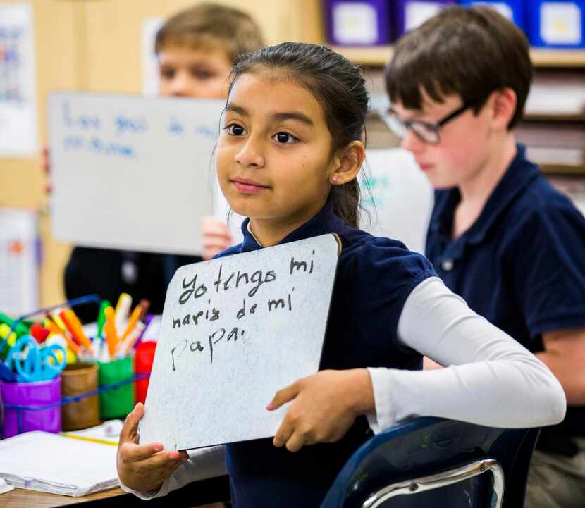 
Emily Vargas, 9, holds up a sentence she wrote in Spanish while third-grade teacher Irma De...