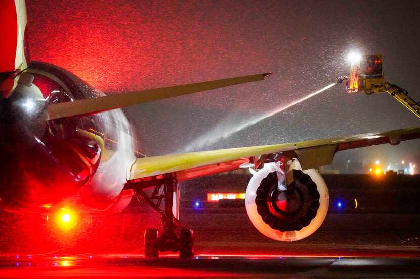 A Qantas Airlines aircraft goes through deicing procedures as snow falls at DFW...