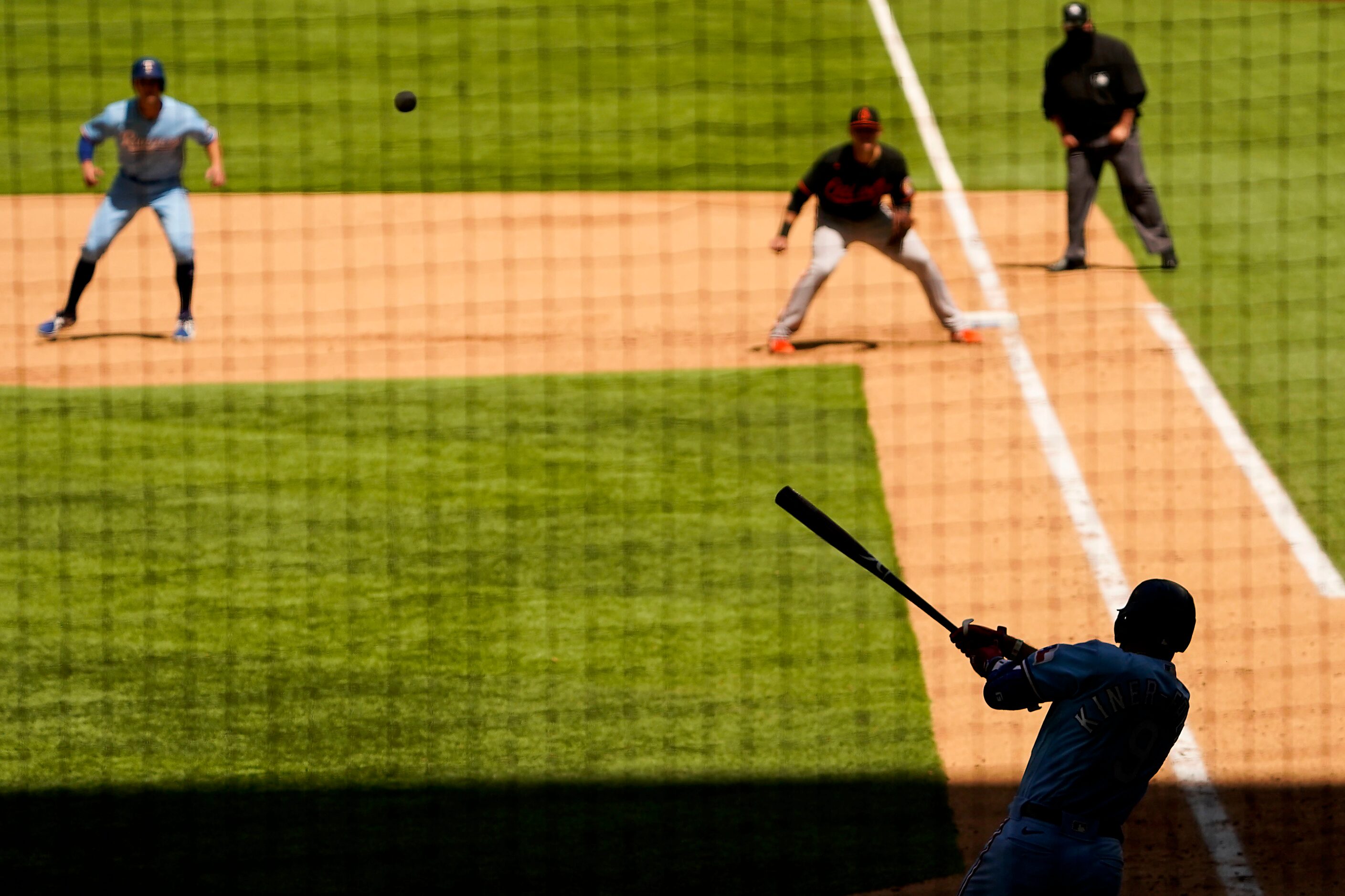 Texas Rangers shortstop Isiah Kiner-Falefa lines out to center field as outfielder Eli White...