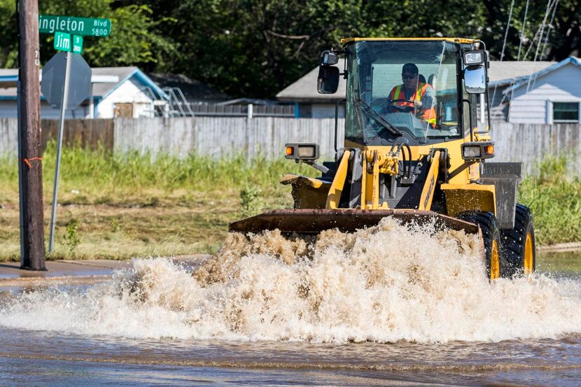 
Dallas street crews pushed water toward pumps May 31 to clear the flooded intersection of...