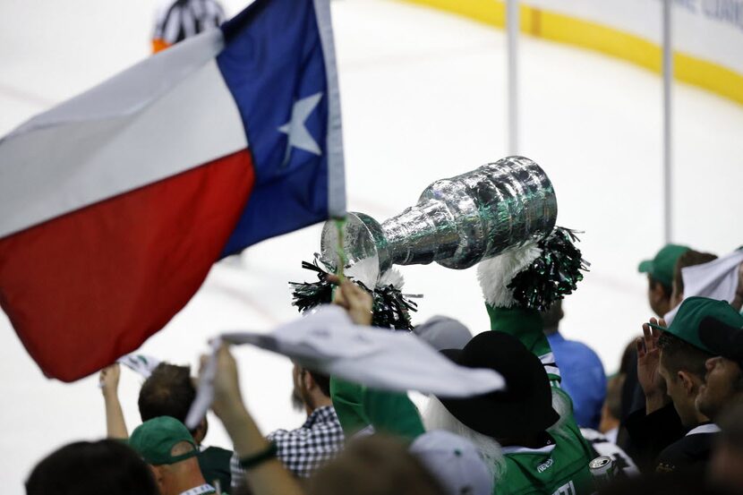 Dallas Stars fans wave the Texas flag and a homemade Stanley Cup in the third period during...