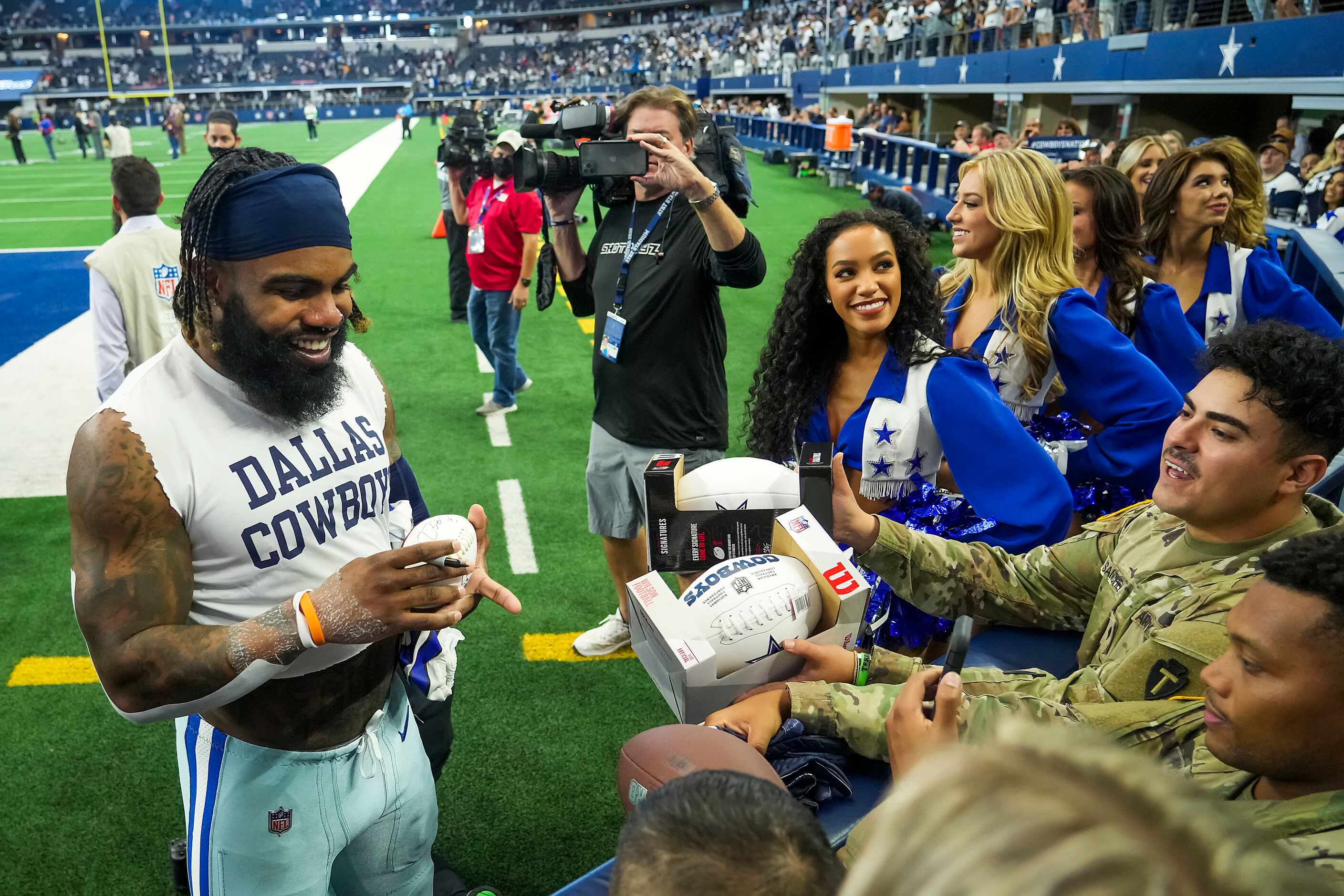 Dallas Cowboys running back Ezekiel Elliott signs autographs for fans as he leaves the field...