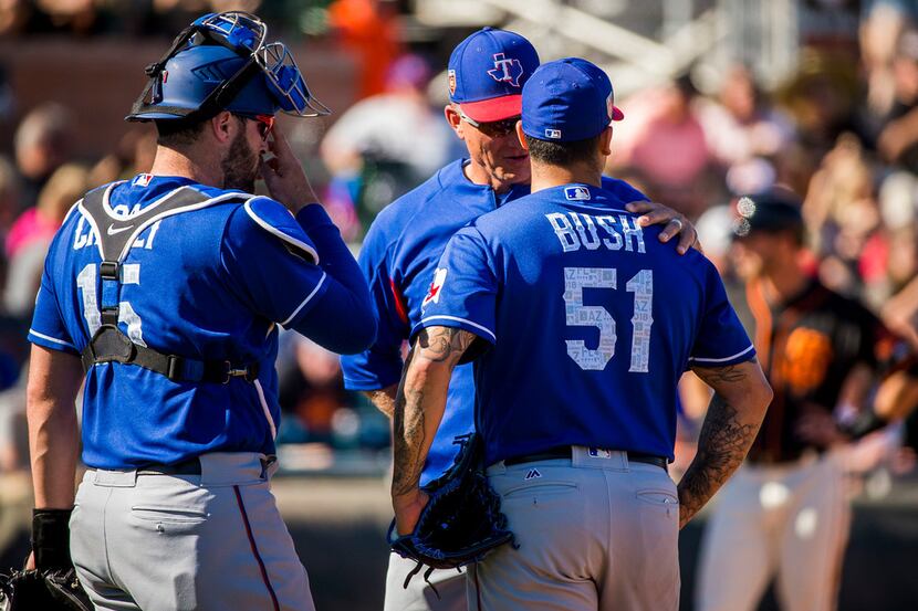 Texas Rangers pitcher Matt Bush gets a visit from manager Jeff Banister and catcher Curt...