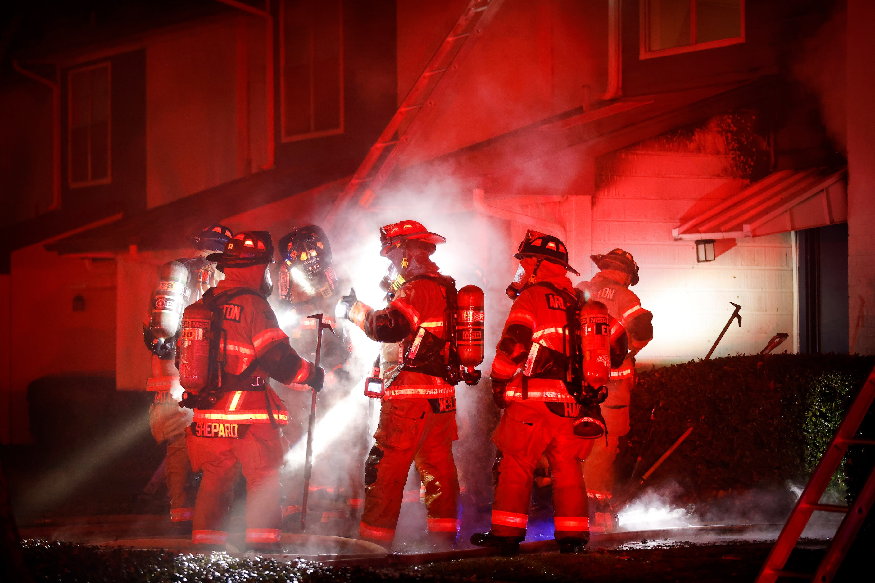 Arlington firefighters huddle after knocking down the flames during a two-alarm fire at the...