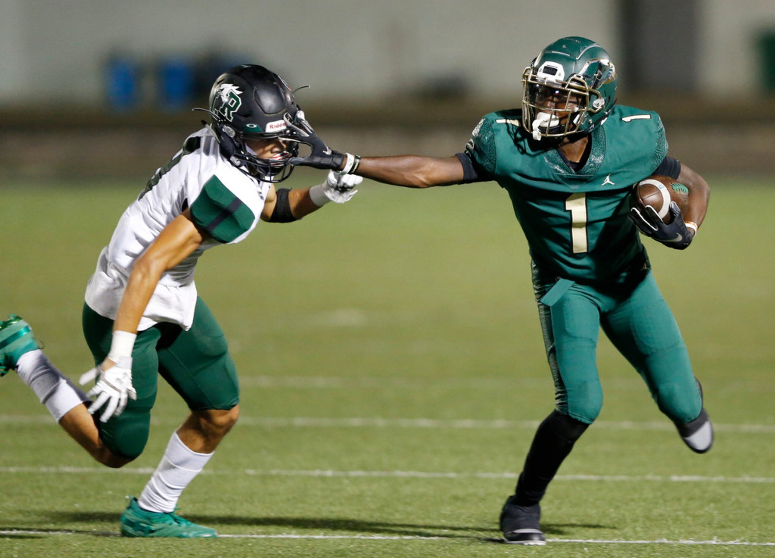 DeSoto's Jordan Brown (1) stiff arms Mansfield Lake Ridge's Omari Oggs (9) during the first...