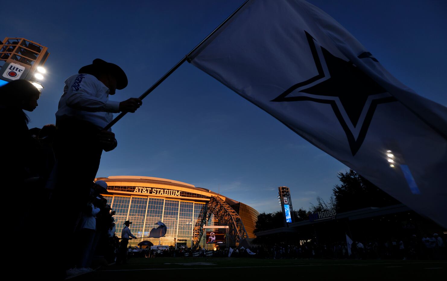 The sun sets on AT&T Stadium as pregame activities take place on the West Plaza before their...