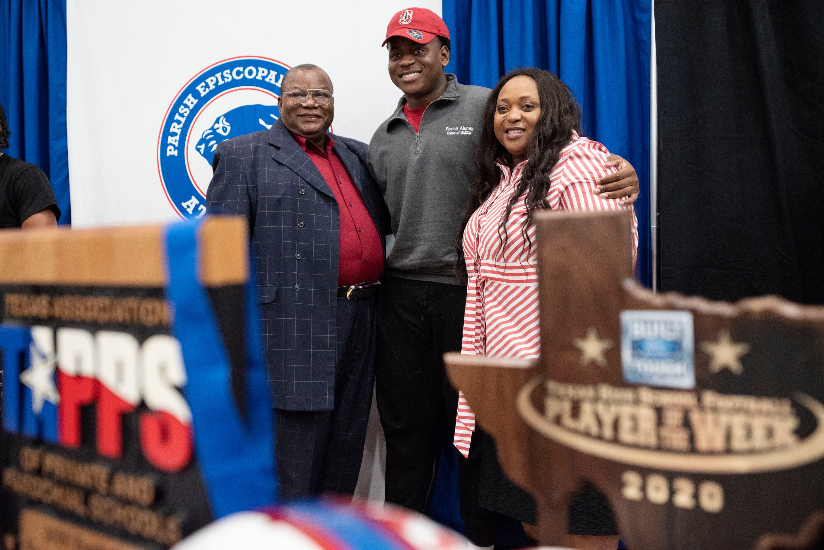 Senior Austin Uke poses for a photo with his parents Augustine Uke, left, and his mother...