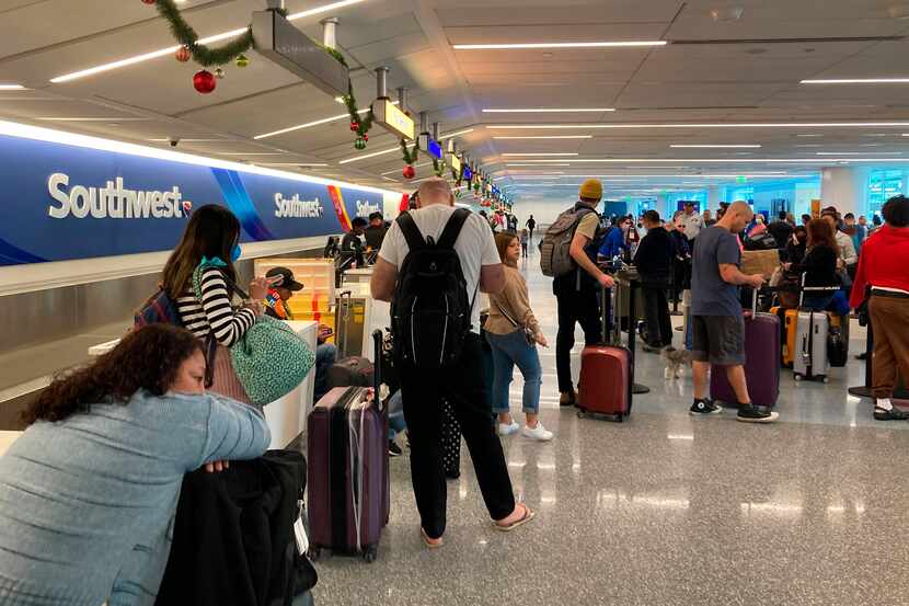 Un grupo de viajeros espera por su equipaje tras tener vuelos cancelados en Southwest...